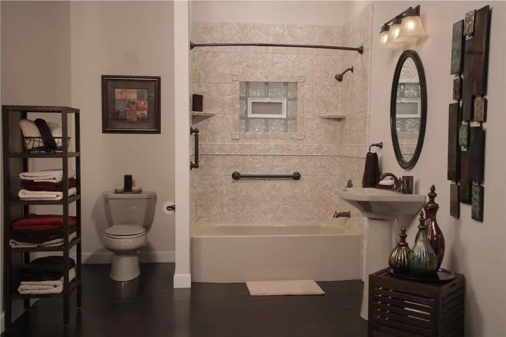 Bathroom with a stone look tub surround, a bronze grab bar, open shelves and a pedestal sink