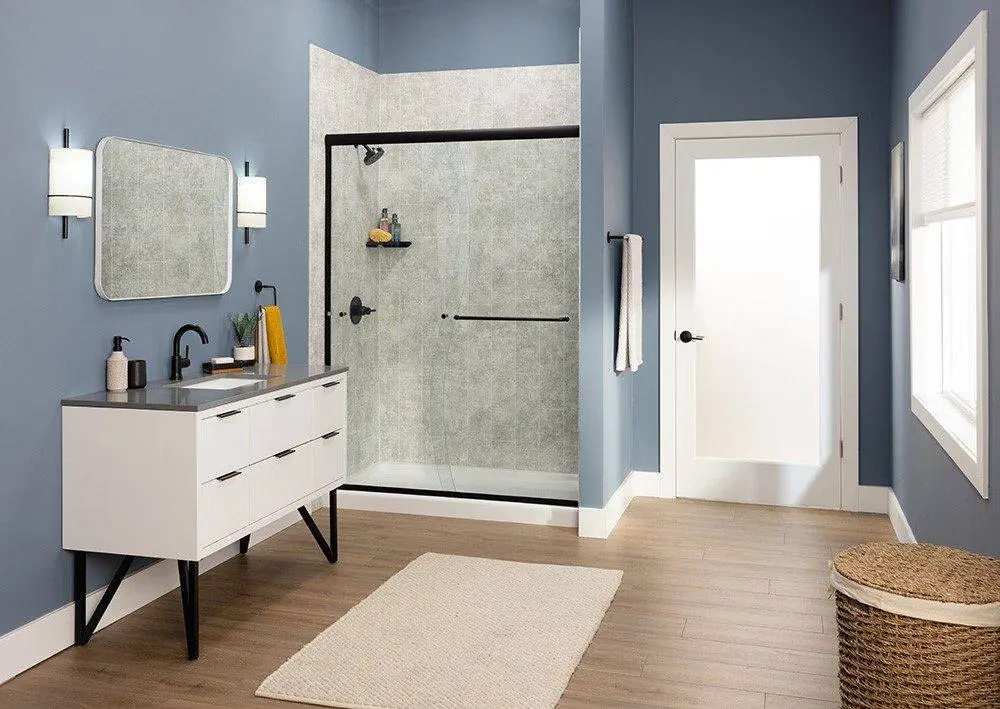 Walk-in shower with a black framed glass door, gray marble look walls and a white vanity