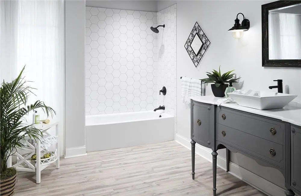 Bathtub with white hexagon tile look walls beside a gray vanity