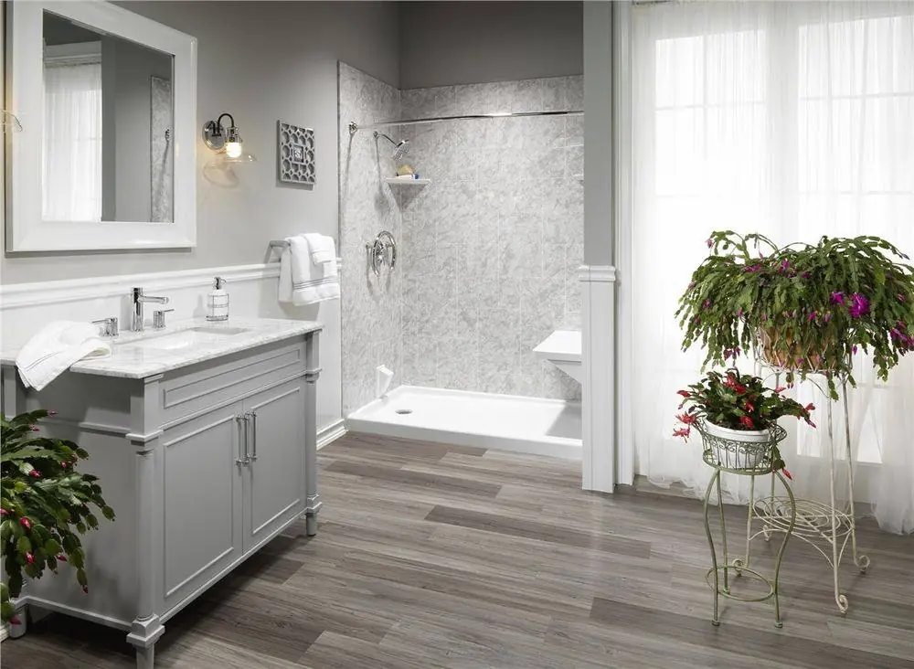 Walk-in shower with a gray marble look surround and a molded corner seat beside a gray vanity
