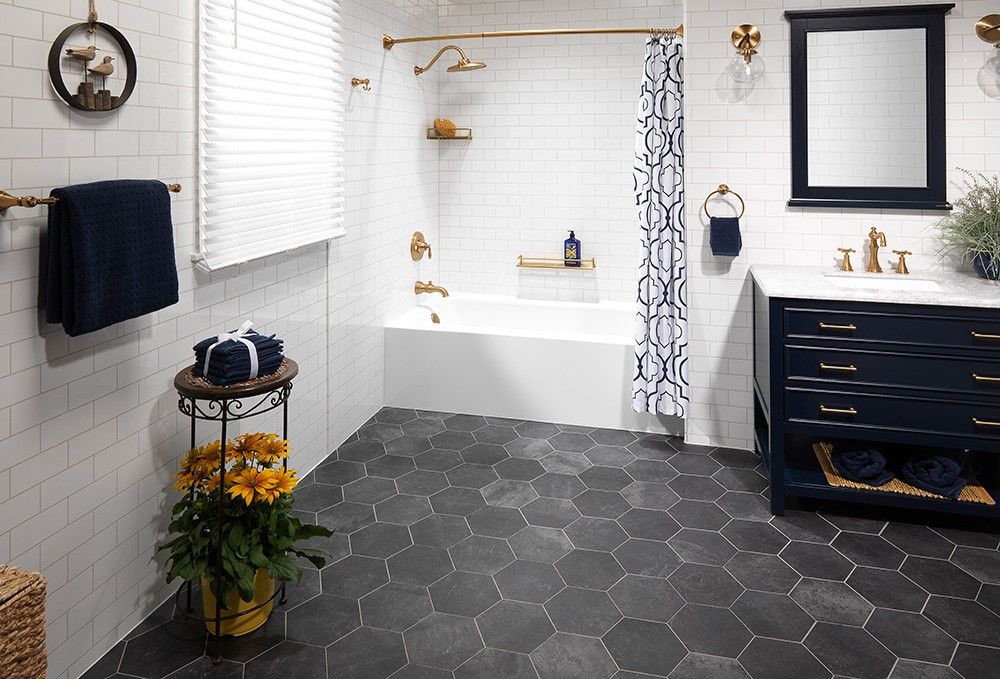 Bathtub with a marble look surround, navy vanity and brushed gold fixtures