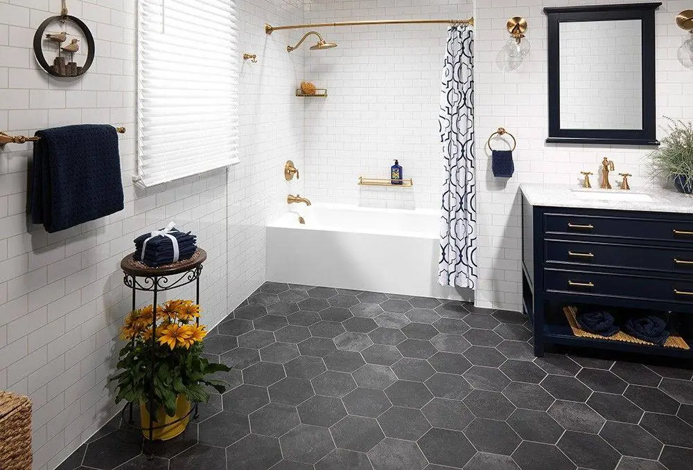 Bathtub with a marble look surround, a navy vanity and brushed gold fixtures