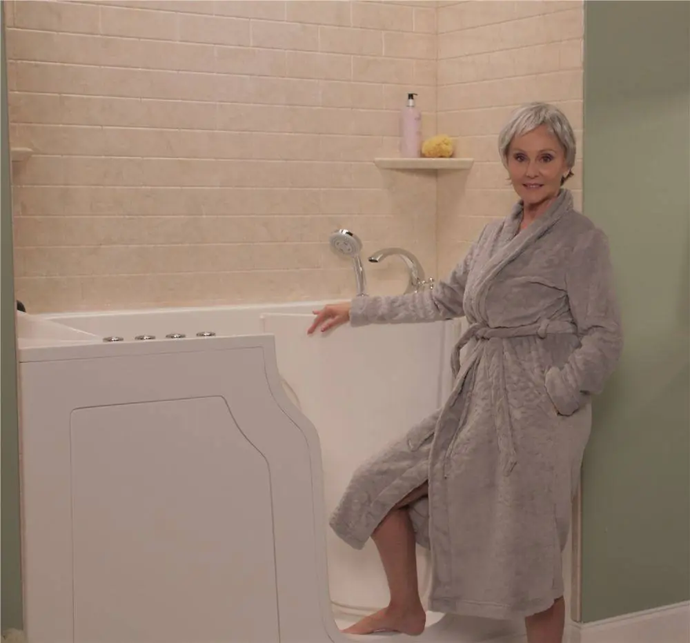 Walk-in tub with a low step door, shown with a homeowner beside it