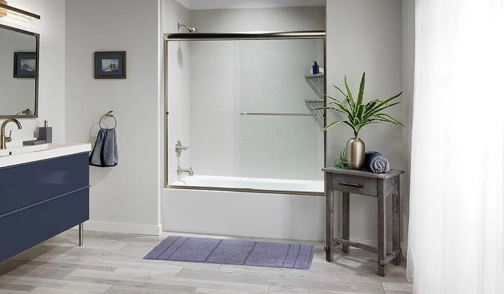 Walk-in shower with gray stone look walls and a black frame glass panel beside a wood vanity