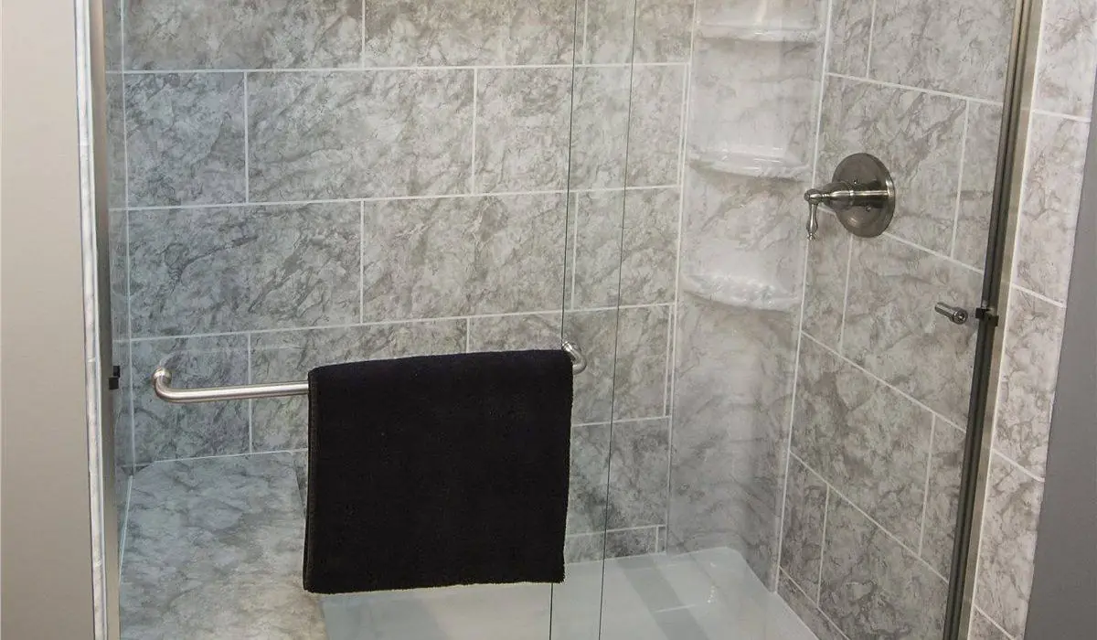 Shower with a framed glass door, a built-in seat and gray stone look walls