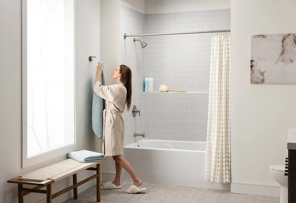 Woman in a robe beside a tub and shower combo with light gray subway look walls, the kind of update done in one day