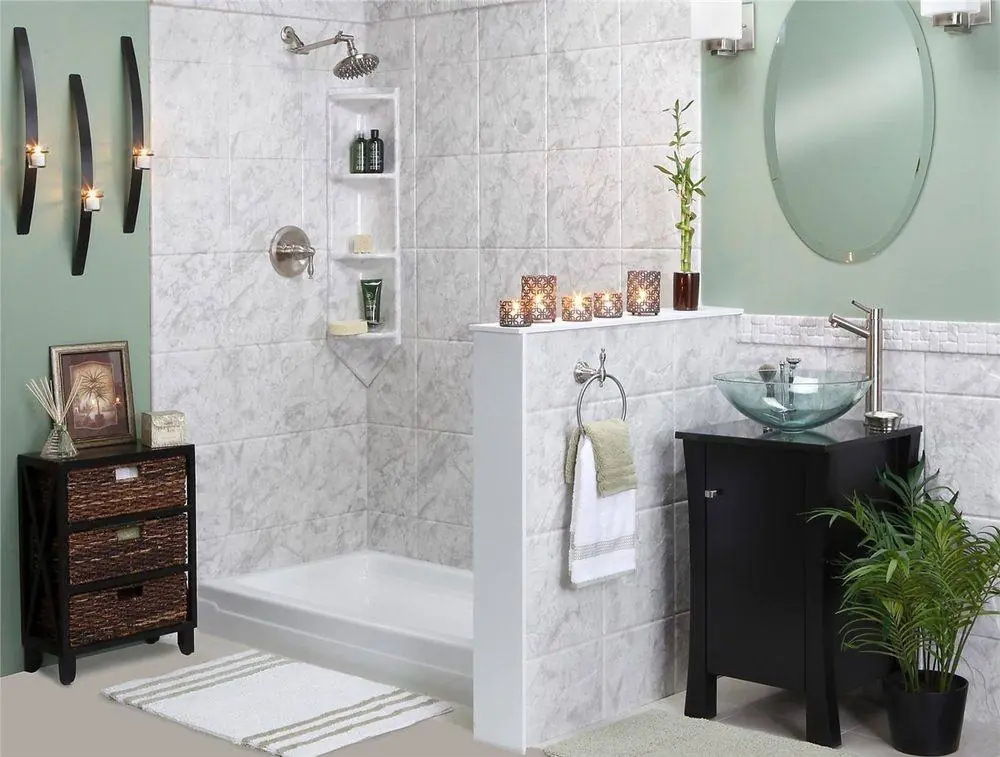 Bathtub with a half wall and a marble look surround beside a vessel sink