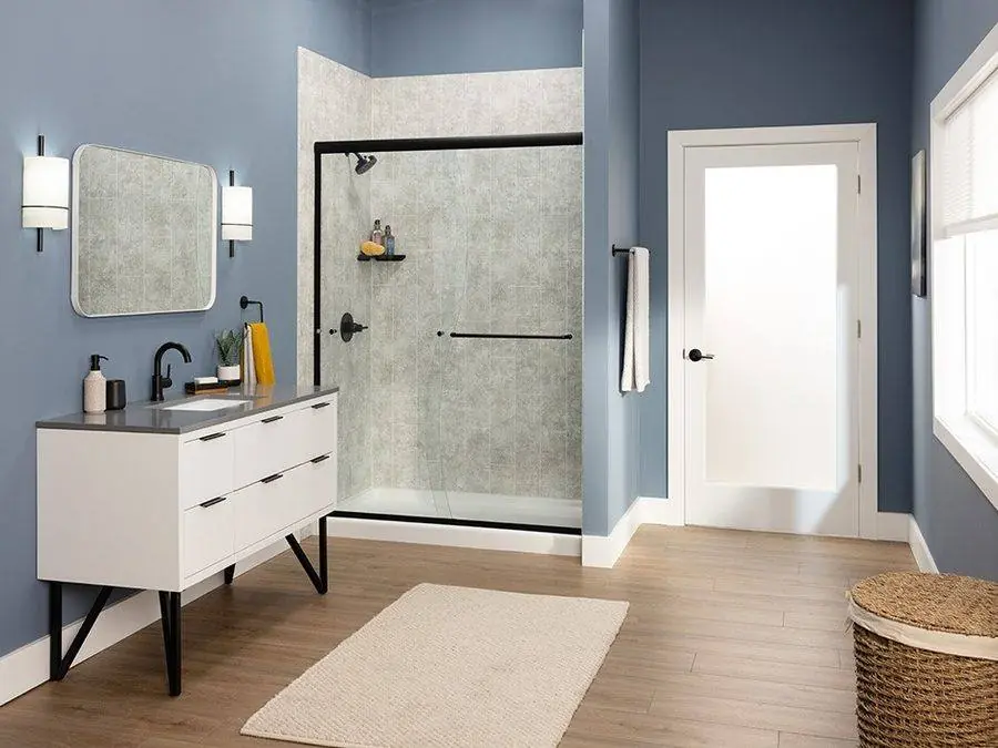 Black framed glass shower door with gray marble look walls and a white vanity