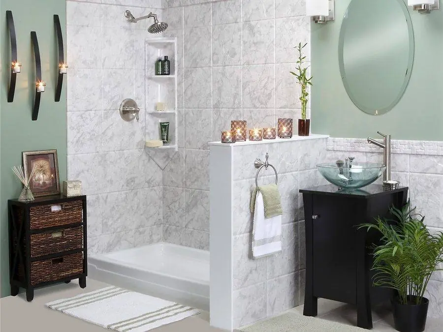 Bathtub with a half wall, marble look surround and a glass vessel sink