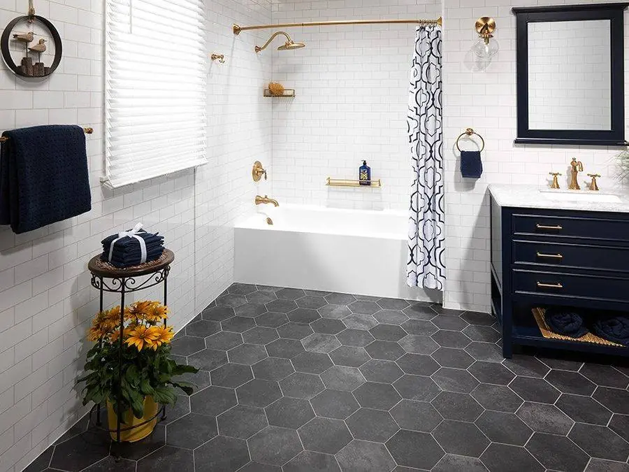 Bathtub with a white tile look surround, navy vanity and hexagon floor