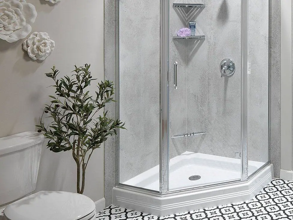 Neo-angle walk-in shower with a chrome framed glass door, grey stone look walls and corner shelves