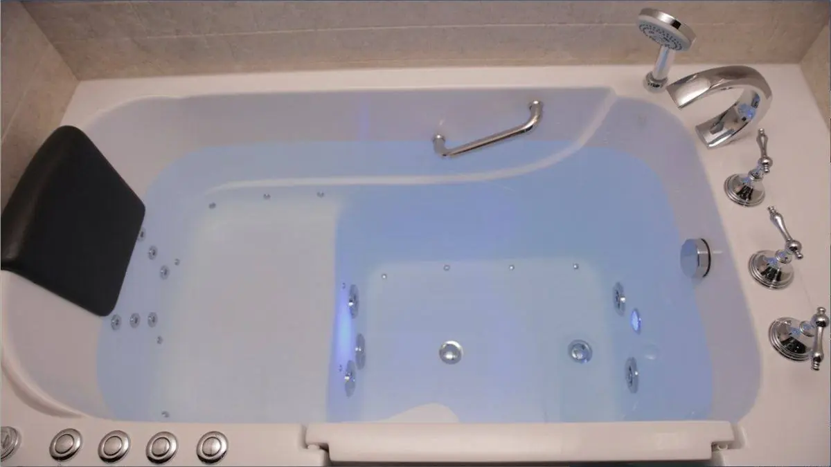 Top view of a walk-in tub with lit hydromassage jets and a padded headrest